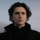 Timothée Chalamet als Paul Atreides in Denis Villeneuves Dune ganz in Schwarz gekleidet in die Ferne starrt.